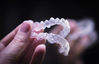 Woman holding a set of clear orthodontic aligners.