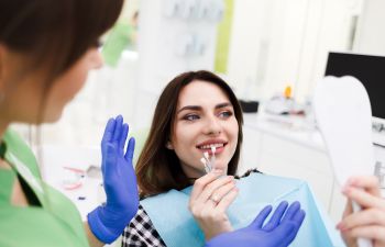 A dentist and a woman in a dental chair choosing dental veneers.