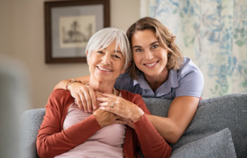 mature daughter with older mother embrace on the sofa